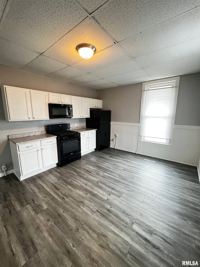 201 N 20th St, East Moline, IL 61244 - kitchen featuring black appliances, a paneled ceiling, a wainscoted wall, white cabinets, and dark wood-type flooring