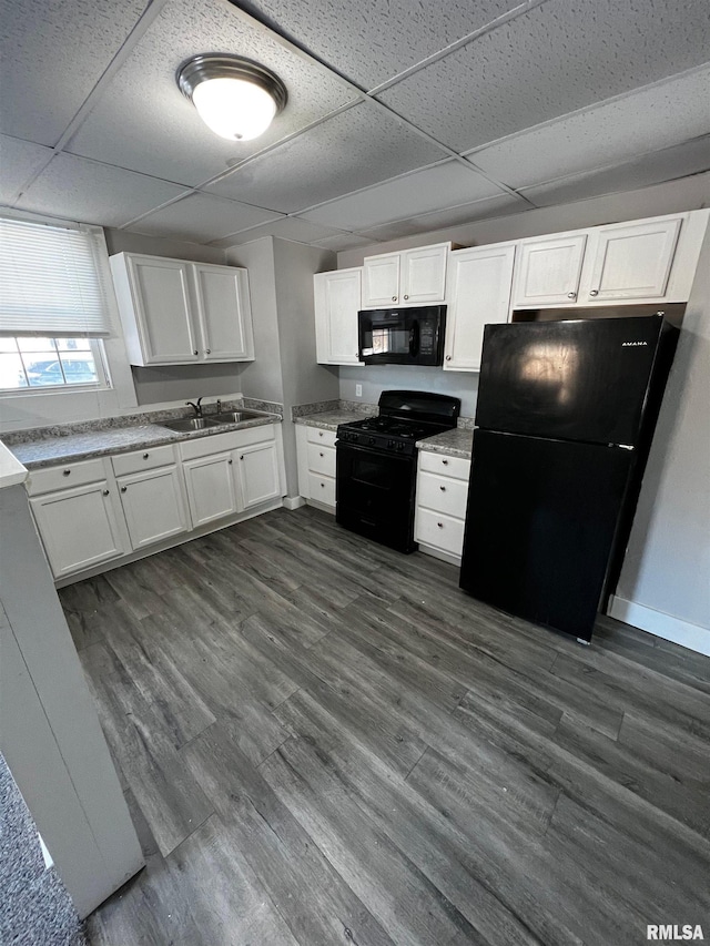 201 N 20th St, East Moline, IL 61244 - kitchen with black appliances, a paneled ceiling, white cabinets, dark wood-style flooring, and light stone counters