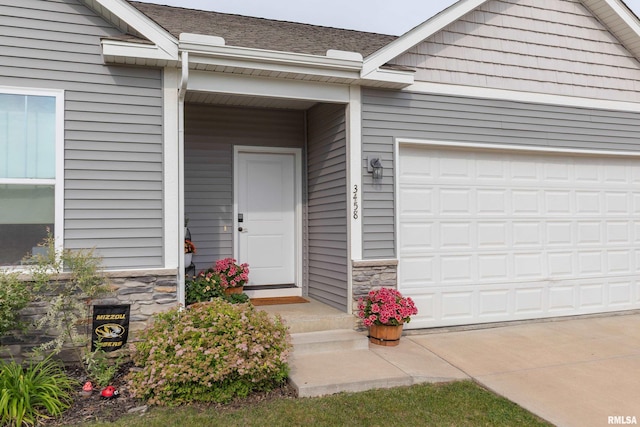 3458 Glenbrook Cir N, Bettendorf, IA 52722 - property entrance with stone siding, concrete driveway, an attached garage, and roof with shingles
