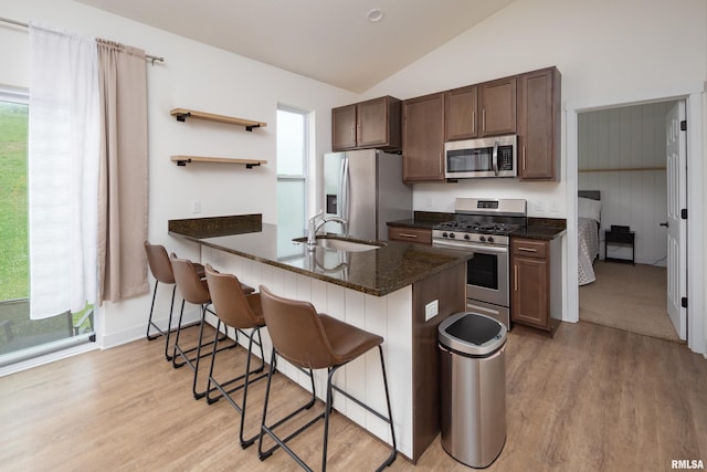 3458 Glenbrook Cir N, Bettendorf, IA 52722 - kitchen with stainless steel appliances, light wood-style floors, a breakfast bar area, lofted ceiling, and open shelves