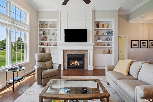 3563 Cobblestone Dr, Bettendorf, IA 52722 - living area with ornamental molding, ceiling fan, wood finished floors, a tiled fireplace, and built in features