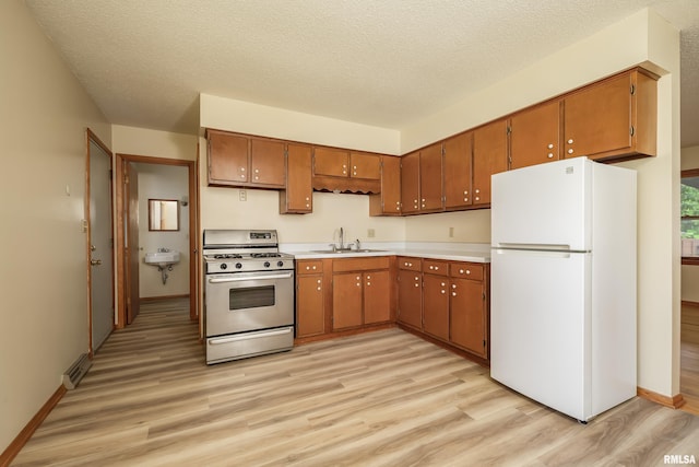 3403 Kimberly Downs Rd, Davenport, IA 52807 - kitchen featuring freestanding refrigerator, stainless steel range with gas stovetop, light wood-type flooring, light countertops, and a textured ceiling
