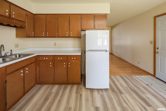 3403 Kimberly Downs Rd, Davenport, IA 52807 - kitchen with freestanding refrigerator, light wood-style floors, brown cabinetry, and light countertops