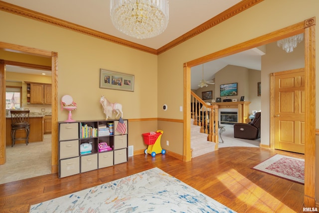 4934 Foxborough Ct, Bettendorf, IA 52722 - rec room with a chandelier, wood finished floors, crown molding, a glass covered fireplace, and ceiling fan