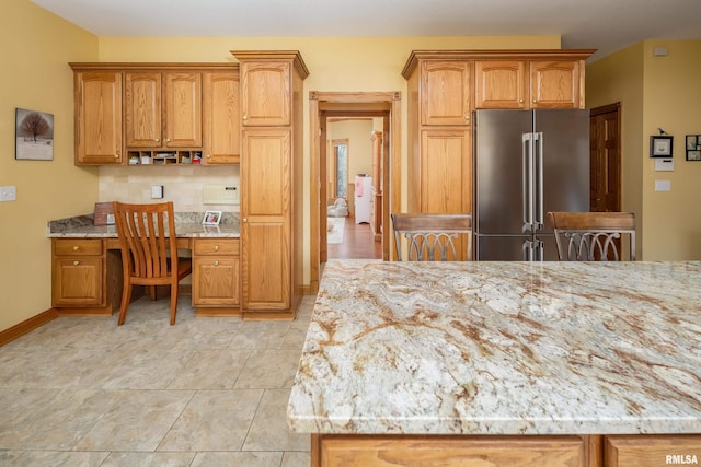 4934 Foxborough Ct, Bettendorf, IA 52722 - kitchen with high end refrigerator, built in desk, light stone countertops, backsplash, and brown cabinetry
