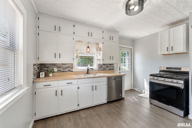 115 4th St, Colona, IL 61241 - kitchen featuring appliances with stainless steel finishes, light wood-style flooring, tasteful backsplash, light countertops, and white cabinetry
