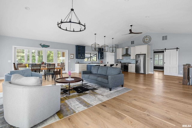 223 N 2nd St, Le Claire, IA 52753 - living area featuring a chandelier, high vaulted ceiling, a barn door, light wood-type flooring, and ceiling fan