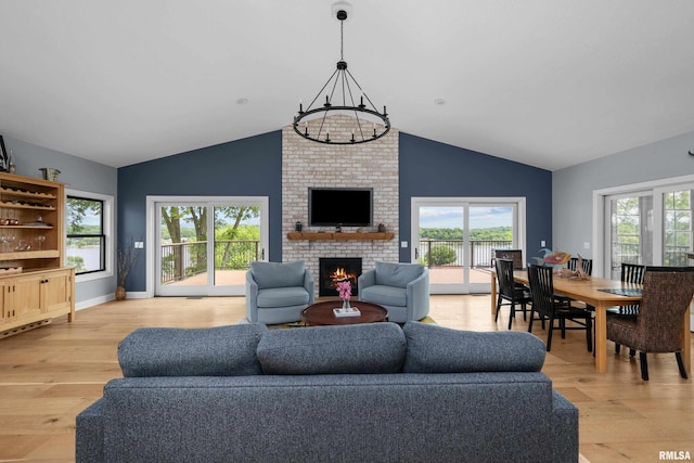 223 N 2nd St, Le Claire, IA 52753 - living area featuring light wood-style floors, a fireplace, a chandelier, lofted ceiling, and healthy amount of natural light