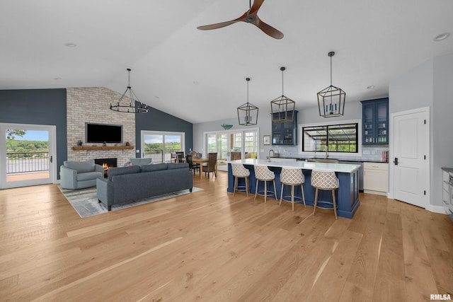 223 N 2nd St, Le Claire, IA 52753 - living room with vaulted ceiling, light wood-style floors, a brick fireplace, and a ceiling fan