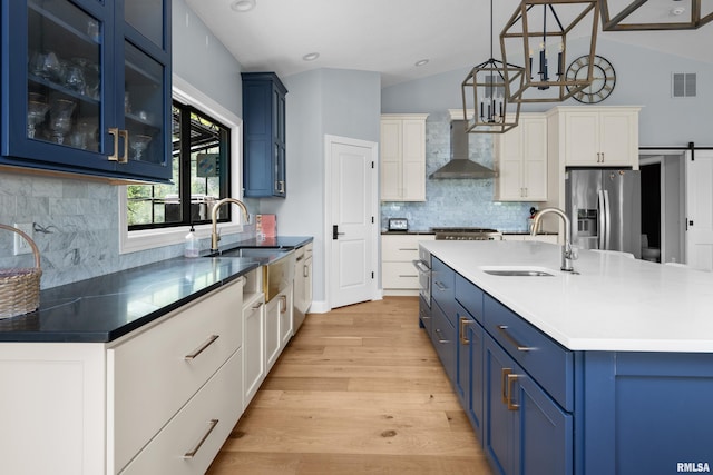 223 N 2nd St, Le Claire, IA 52753 - kitchen featuring blue cabinetry, stainless steel fridge with ice dispenser, wall chimney exhaust hood, light wood-type flooring, and decorative backsplash