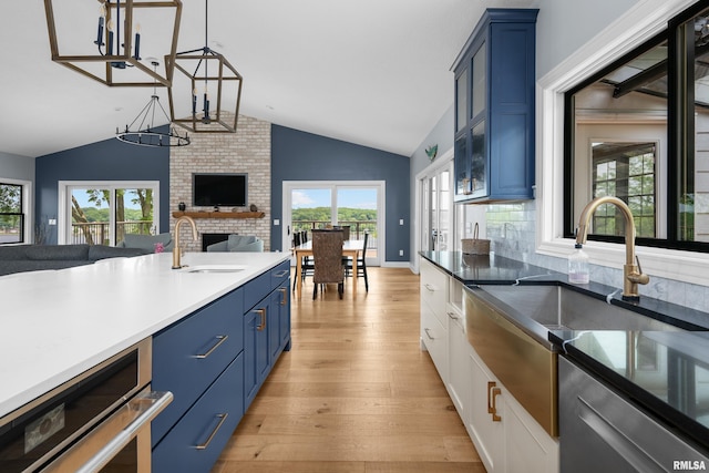 223 N 2nd St, Le Claire, IA 52753 - kitchen with blue cabinetry, lofted ceiling, open floor plan, a brick fireplace, and a chandelier