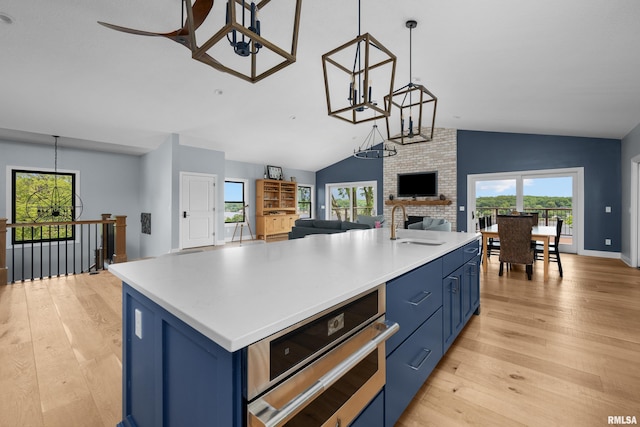 223 N 2nd St, Le Claire, IA 52753 - kitchen with blue cabinets, open floor plan, light wood-style flooring, vaulted ceiling, and ceiling fan