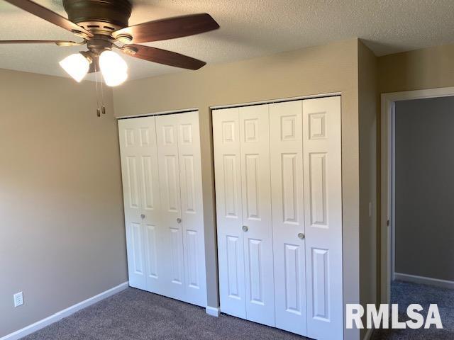 2616 W 56th St, Davenport, IA 52806 - unfurnished bedroom with dark colored carpet, two closets, a ceiling fan, and a textured ceiling