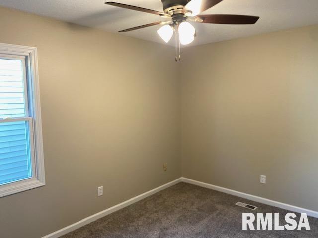 2616 W 56th St, Davenport, IA 52806 - spare room featuring a ceiling fan, dark colored carpet, and healthy amount of natural light