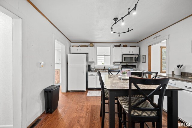 406 234th St, Aledo, IL 61231 - kitchen with freestanding refrigerator, stainless steel microwave, white cabinetry, wood finished floors, and ornamental molding