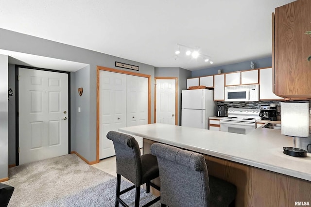 109 E Price St Unit 203, Eldridge, IA 52748 - kitchen with white appliances, a peninsula, light countertops, a breakfast bar, and light colored carpet