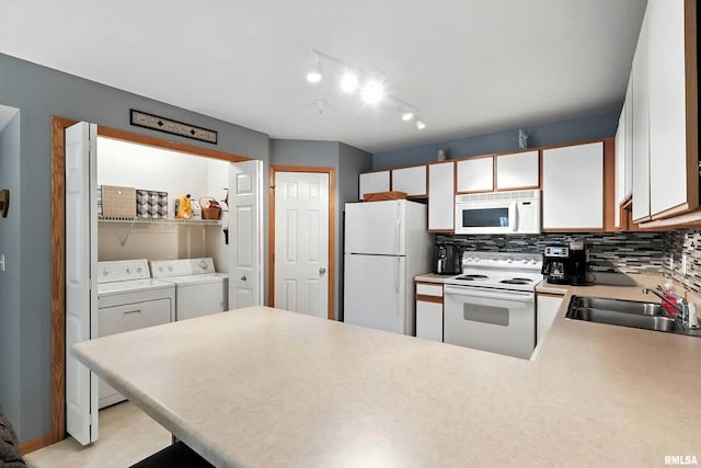 109 E Price St Unit 203, Eldridge, IA 52748 - kitchen featuring white appliances, washing machine and clothes dryer, a peninsula, tasteful backsplash, and light countertops