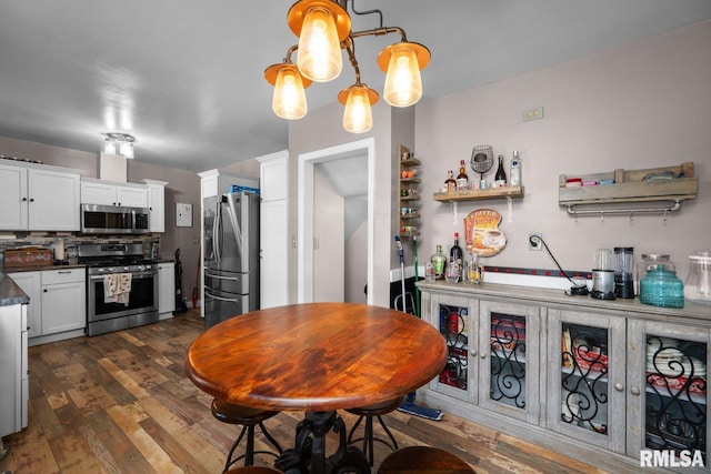 2207 4th St Unit A, East Moline, IL 61244 - kitchen featuring appliances with stainless steel finishes, dark wood finished floors, dark countertops, white cabinetry, and tasteful backsplash