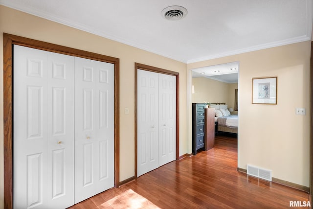 17 Wildwood Trl, Bettendorf, IA 52722 - unfurnished bedroom with two closets, wood finished floors, and ornamental molding