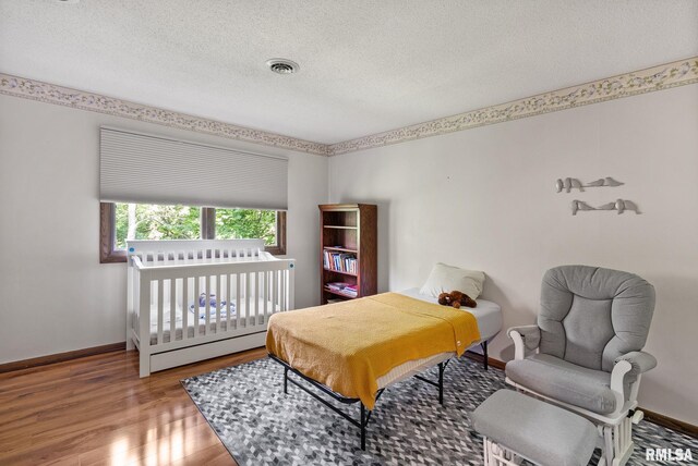 17 Wildwood Trl, Bettendorf, IA 52722 - bedroom featuring a textured ceiling and wood finished floors