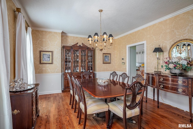 2806 E 42nd Ct, Davenport, IA 52807 - dining room with wallpapered walls, a wainscoted wall, a chandelier, wood finished floors, and ornamental molding