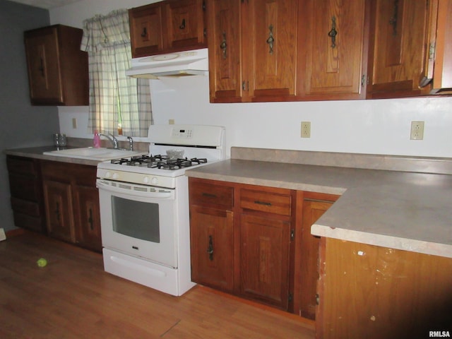32 Crescent Lk, Alpha, IL 61413 - kitchen with white gas range, premium range hood, light wood finished floors, and brown cabinets