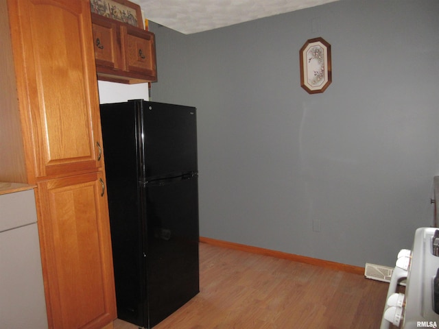 32 Crescent Lk, Alpha, IL 61413 - kitchen with freestanding refrigerator, light wood finished floors, and brown cabinetry
