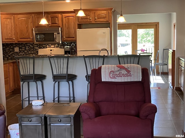 420 E Garfield St, Kewanee, IL 61443 - kitchen featuring stainless steel microwave, fridge, dark tile patterned floors, a center island, and decorative backsplash