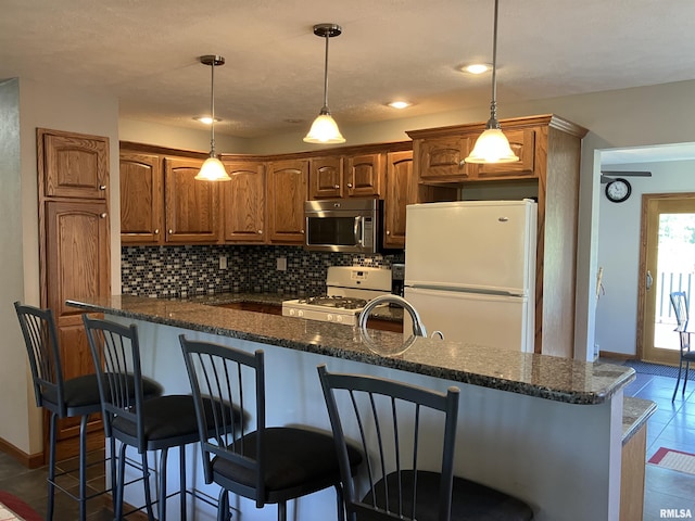420 E Garfield St, Kewanee, IL 61443 - kitchen with white appliances, dark tile patterned floors, tasteful backsplash, a kitchen bar, and brown cabinetry