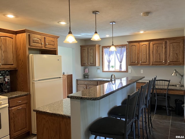 420 E Garfield St, Kewanee, IL 61443 - kitchen with a center island, freestanding refrigerator, dark stone countertops, a kitchen breakfast bar, and brown cabinetry