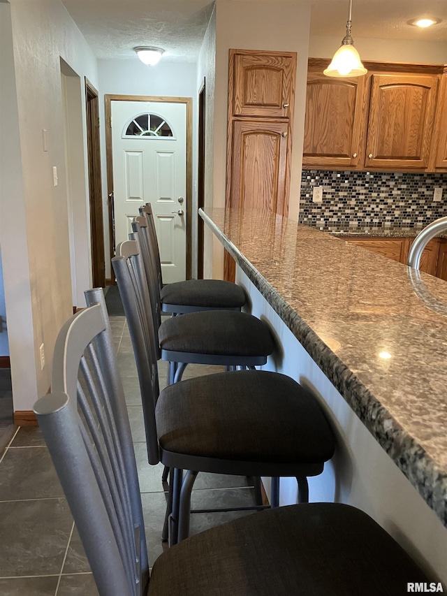 420 E Garfield St, Kewanee, IL 61443 - kitchen with tasteful backsplash, brown cabinets, a breakfast bar area, and dark countertops