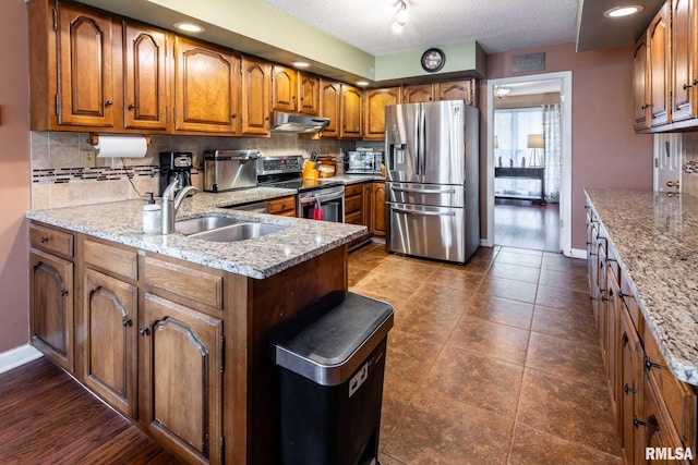 1814 Testa Dr, Marion, IL 62959 - kitchen featuring appliances with stainless steel finishes, brown cabinets, under cabinet range hood, tasteful backsplash, and a textured ceiling