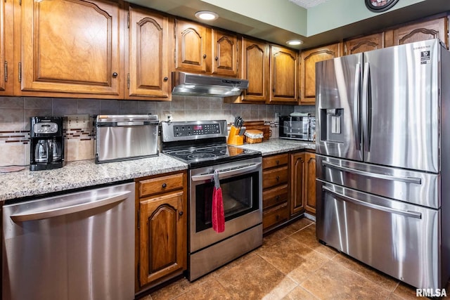 1814 Testa Dr, Marion, IL 62959 - kitchen with appliances with stainless steel finishes, under cabinet range hood, brown cabinetry, and tasteful backsplash
