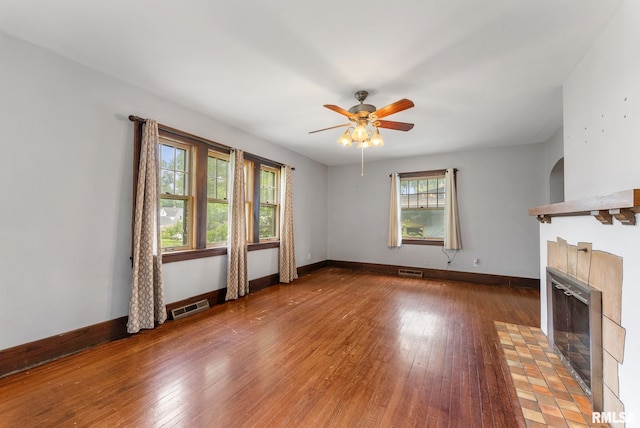 921 45th St, Rock Island, IL 61201 - unfurnished living room with a tiled fireplace, ceiling fan, and wood-type flooring