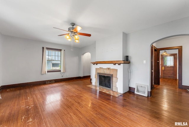 921 45th St, Rock Island, IL 61201 - unfurnished living room featuring arched walkways, plenty of natural light, a ceiling fan, and a tile fireplace