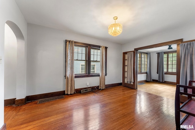 921 45th St, Rock Island, IL 61201 - spare room featuring arched walkways, wood-type flooring, and a chandelier