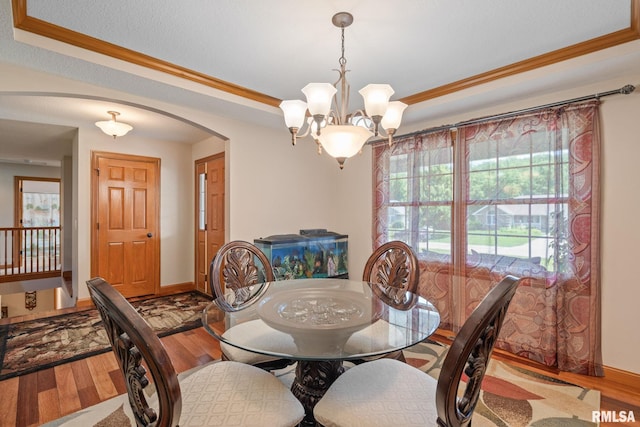 10984 150th St, Davenport, IA 52804 - dining space featuring arched walkways, a raised ceiling, wood finished floors, a chandelier, and ornamental molding