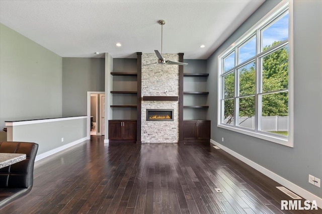 6691 Spring Creek Dr, Bettendorf, IA 52722 - unfurnished living room featuring dark wood-style flooring, a fireplace, a textured ceiling, built in shelves, and recessed lighting