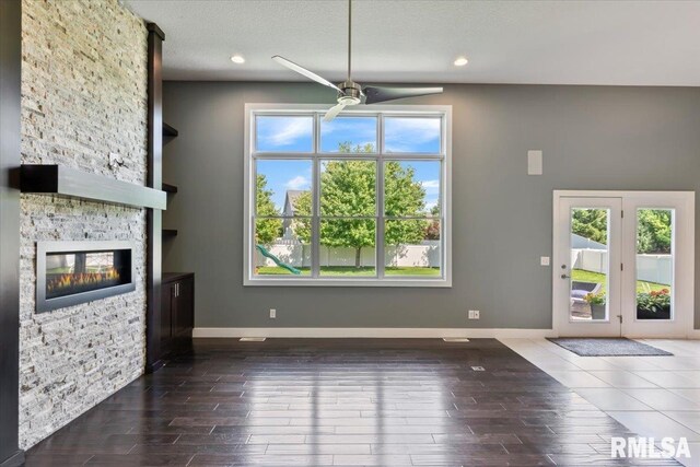 6691 Spring Creek Dr, Bettendorf, IA 52722 - unfurnished living room with a ceiling fan, a stone fireplace, wood finished floors, recessed lighting, and a textured ceiling