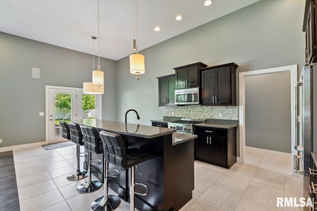6691 Spring Creek Dr, Bettendorf, IA 52722 - kitchen with appliances with stainless steel finishes, dark stone countertops, a towering ceiling, decorative backsplash, and a kitchen bar