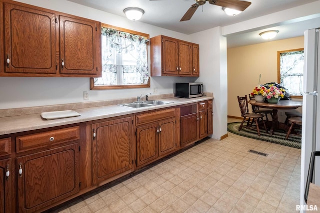 105 Laurel St, Stonefort, IL 62987 - kitchen with stainless steel microwave, light floors, a ceiling fan, brown cabinetry, and light countertops
