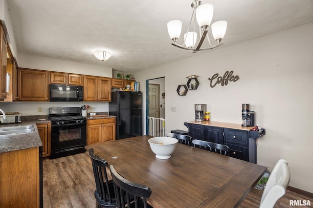 209 Hilltop St, Colona, IL 61241 - kitchen with black appliances, dark countertops, brown cabinets, a chandelier, and dark wood-style flooring