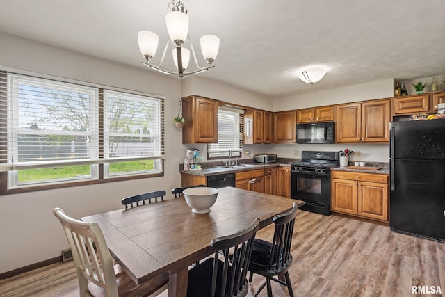 209 Hilltop St, Colona, IL 61241 - kitchen featuring black appliances, a chandelier, brown cabinets, light wood finished floors, and hanging light fixtures