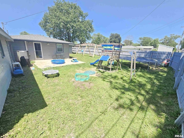2409 9th St, Silvis, IL 61282 - fenced backyard with a trampoline, a playground, an outdoor fire pit, and a patio area