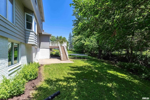 4345 Amesbury Dr, Bettendorf, IA 52722 - view of grassy yard with stairway, a trampoline, a patio area, and a deck