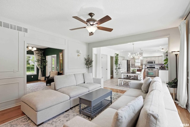 1200 Bridgeview Place, Le Claire, IA 52753 - living area featuring a chandelier, a decorative wall, ceiling fan, and light wood-type flooring