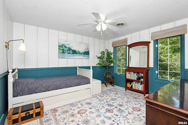 1200 Bridgeview Place, Le Claire, IA 52753 - carpeted bedroom with a textured ceiling, a decorative wall, and ceiling fan