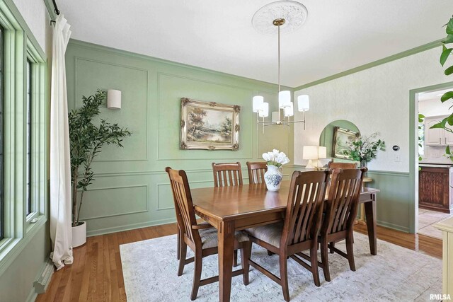 1200 Bridgeview Place, Le Claire, IA 52753 - dining room featuring wood finished floors, a decorative wall, ornamental molding, and a chandelier