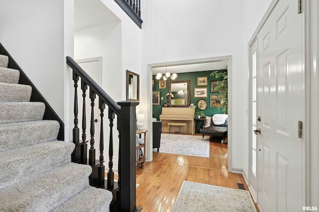 1200 Bridgeview Place, Le Claire, IA 52753 - foyer featuring light wood-type flooring, a chandelier, stairway, and a towering ceiling