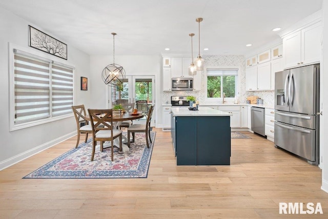 1100 Wild W Dr, Le Claire, IA 52753 - kitchen with stainless steel appliances, a center island, white cabinets, light countertops, and decorative backsplash
